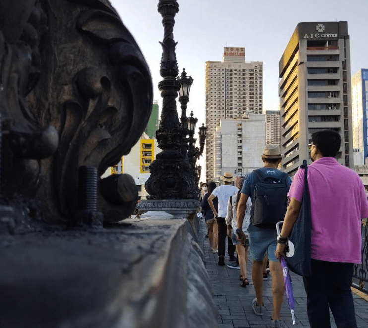 people walking on a bridge in manila
