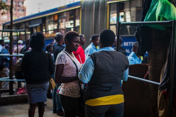 Two women talking in front of the bus. One of them is a transport worker.